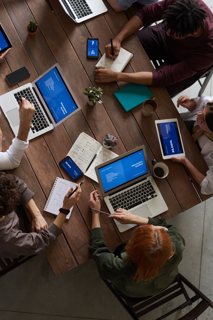 portfolio-06 A diverse group of professionals brainstorming with laptops and notepads in a modern office.