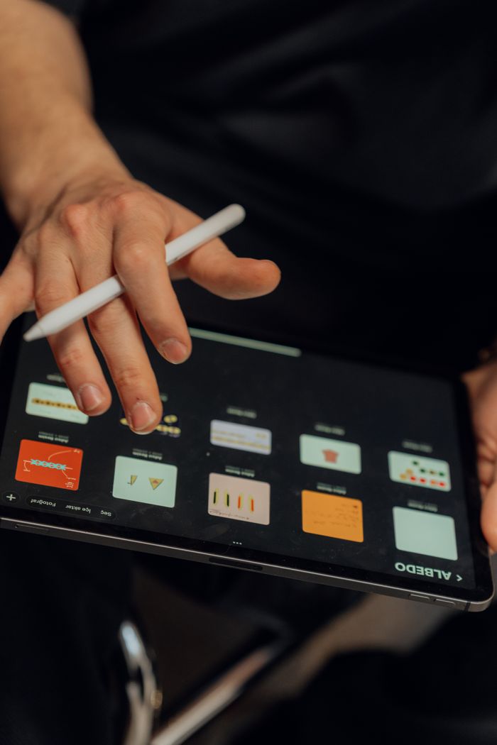 why-choose-us A person working on a digital tablet with a stylus, creating designs using an application.